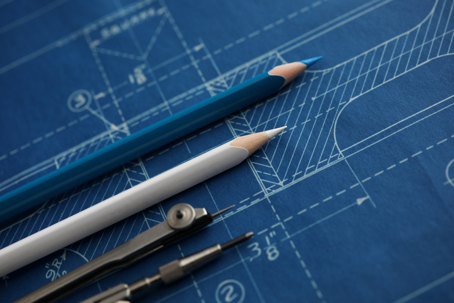 Drawing tools lying over blueprint paper.