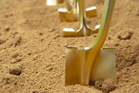 Gold shovels stuck in the dirt, in preparation of a groundbreaking ceremony.